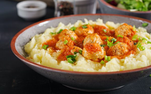 Meatballs in tomato sauce with mashed potatoes in bowl.